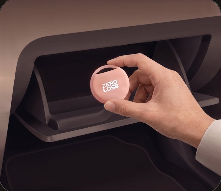 A hand pressing the tracker into place inside a car